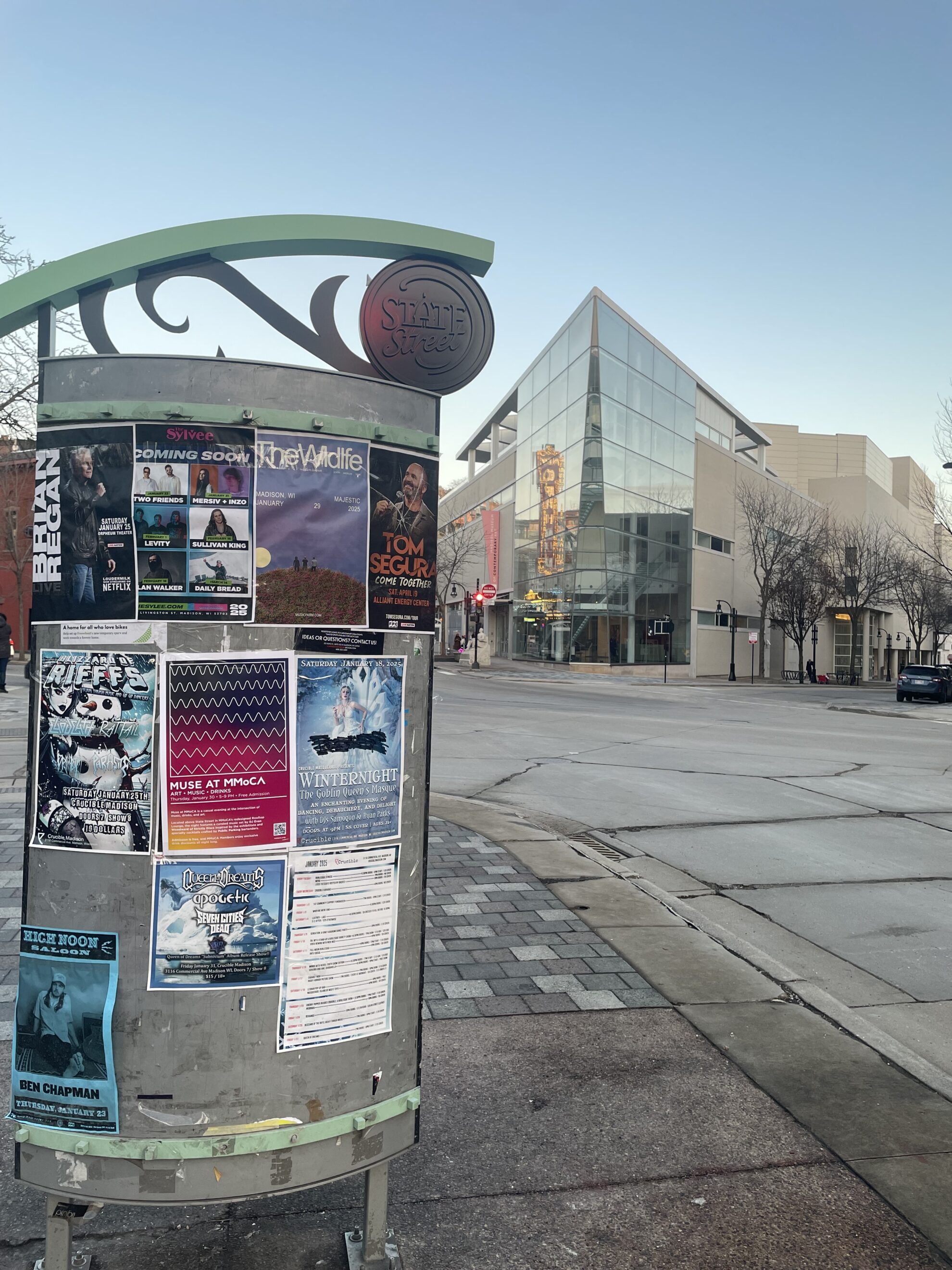 A panel with posters and a glass building in the background.