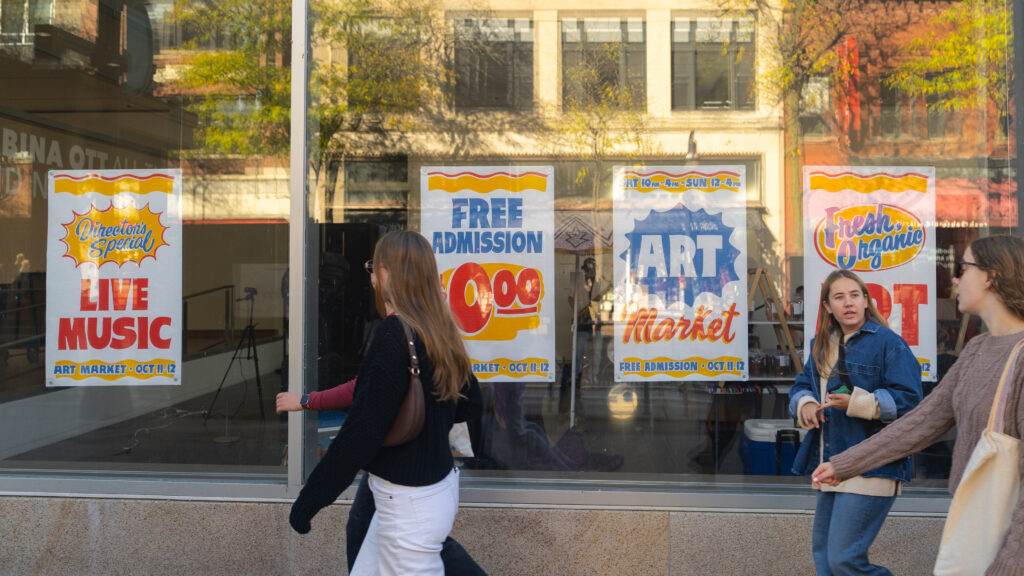 Students walking past Art Market posters