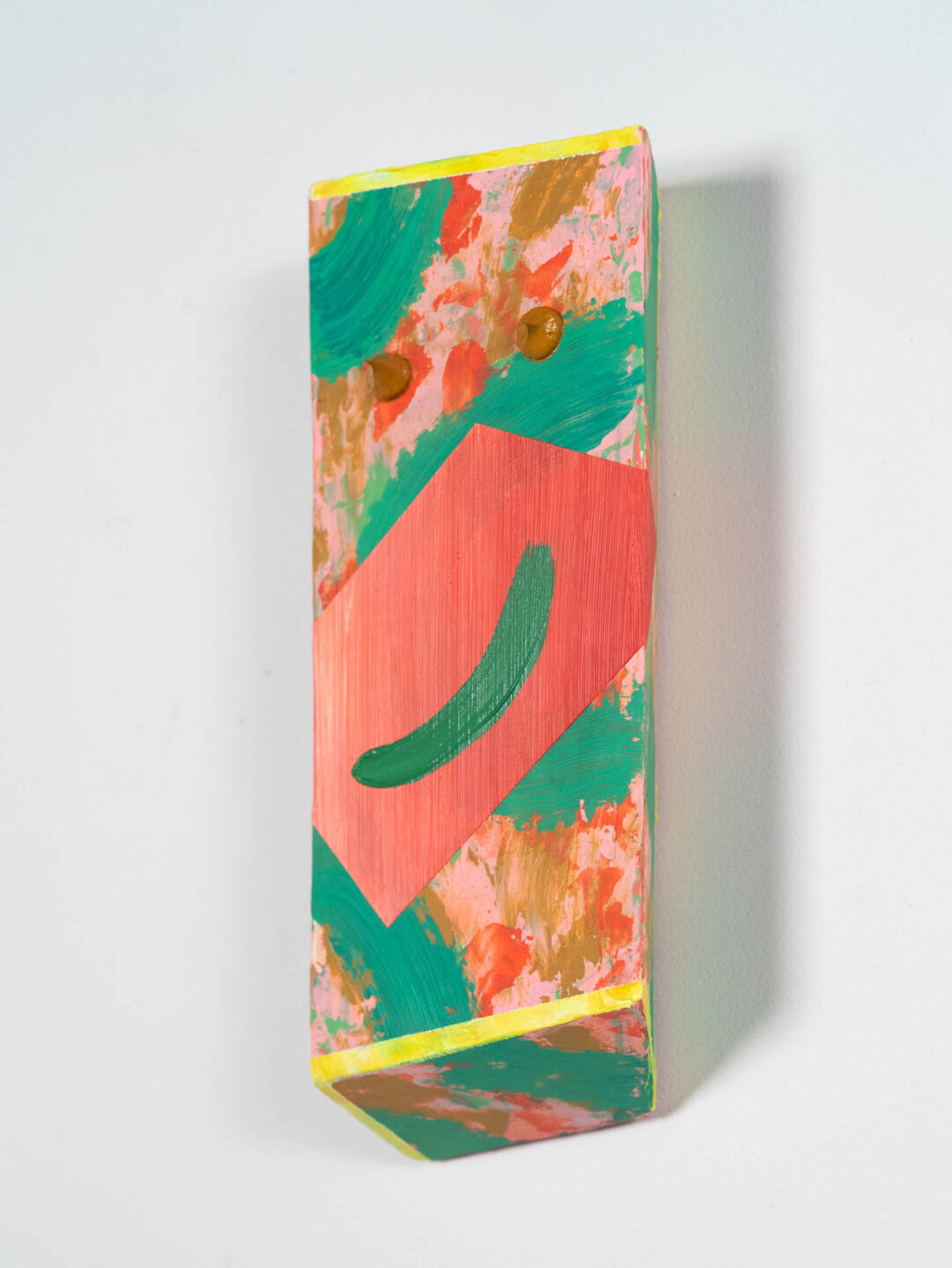 An abstract wall mounted sculpture of pink and green